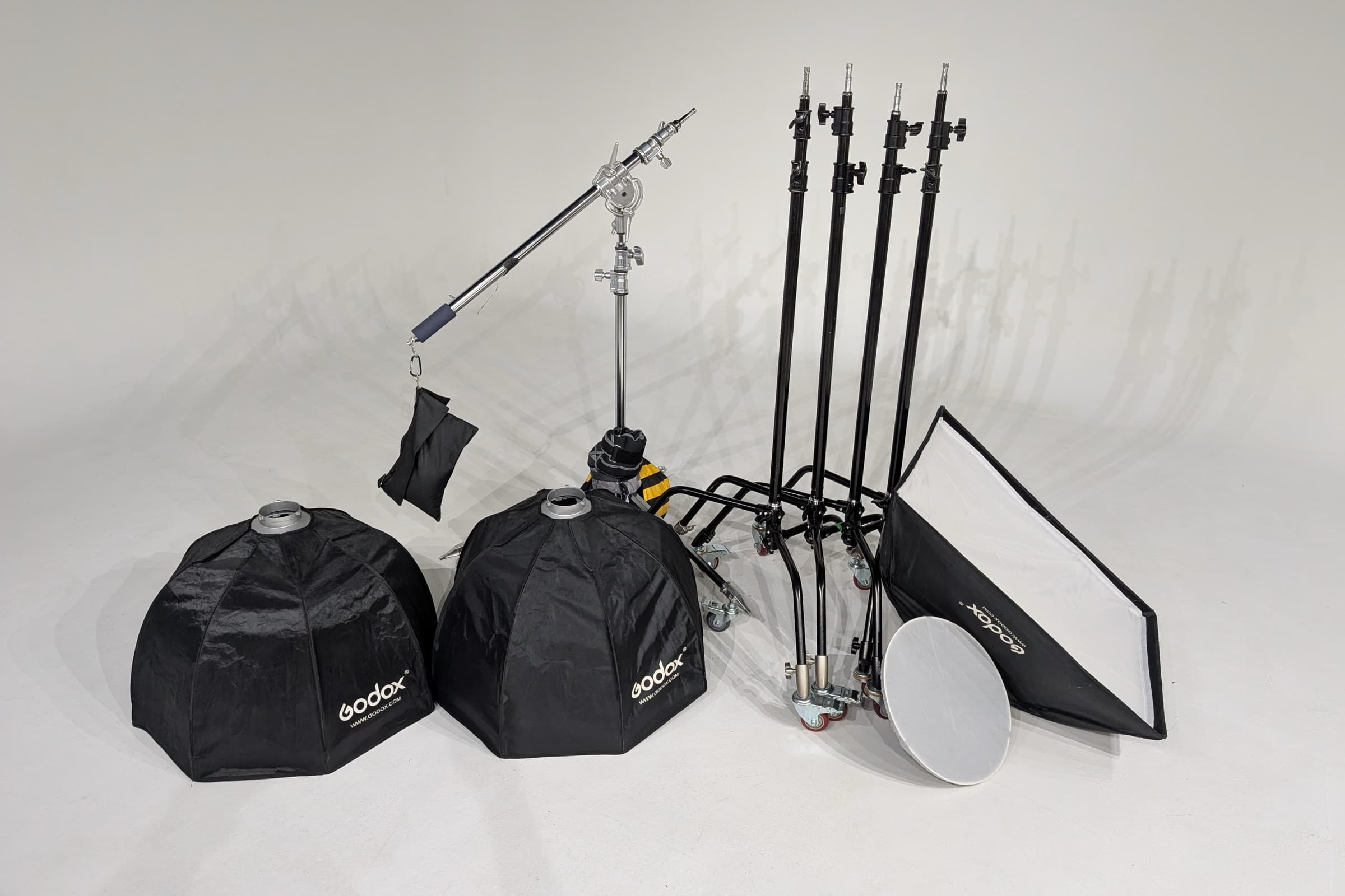 Two octaboxes, a rectangular softbox, a beauty dish, a boom stand with sandbag and four rolling stands laid out on the cyc